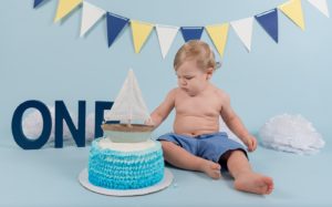One year old boy touching his cake at a nautical cake smash