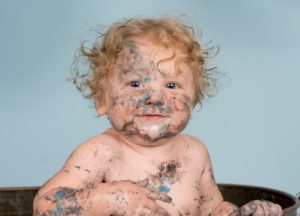 Close up of a one year old boy covered in cake