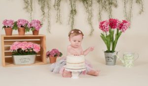 One year old girl beating on her cake