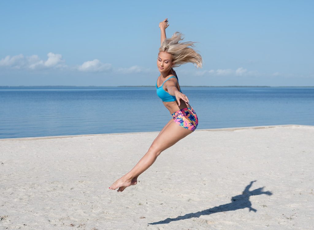 Senior girl dancing on the beach jumping with her legs together