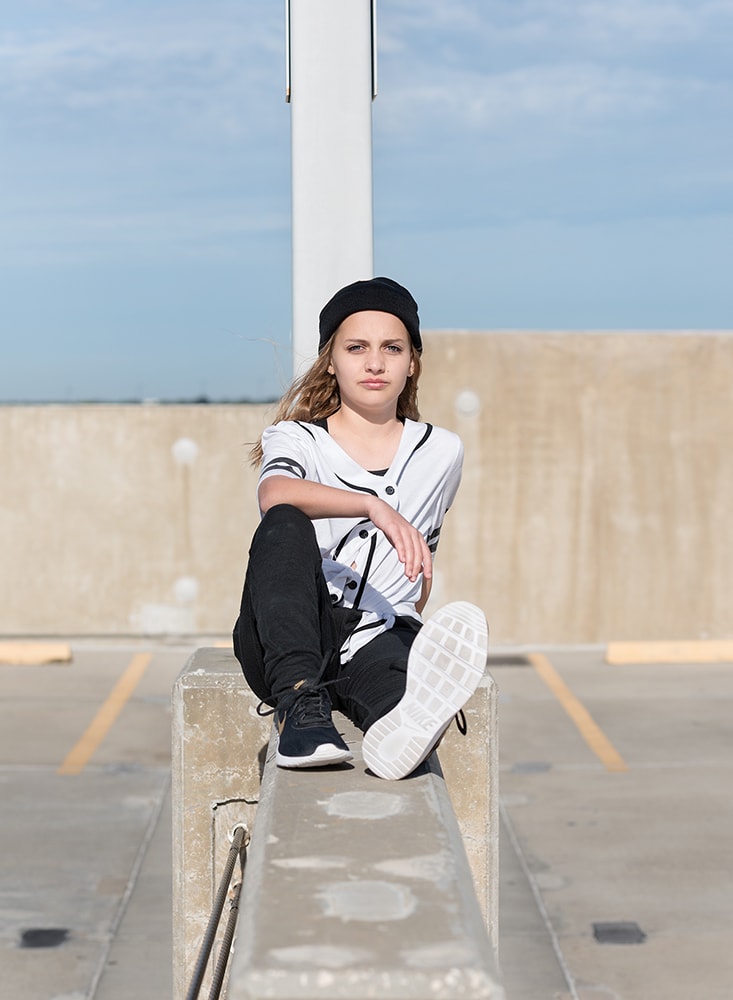 Tween girl sitting on a parking garage wall