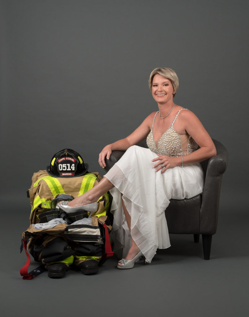 Lady in a white gown sat next to fire-fighting gear