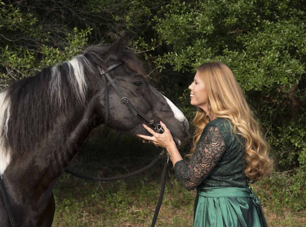 Lady in a green gown facing her black and white horse