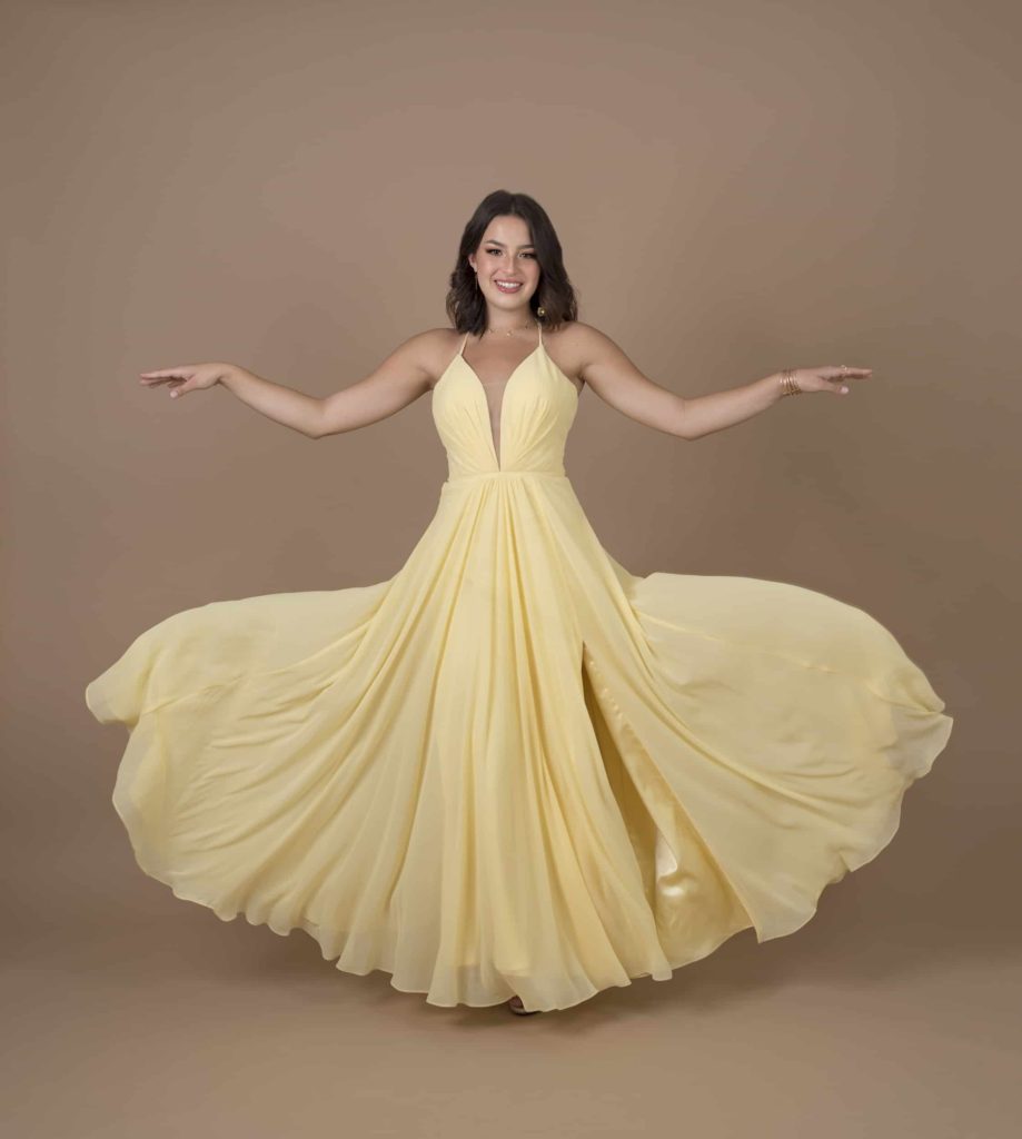 Senior girl in a yellow dress with her arms out and her dress flowing