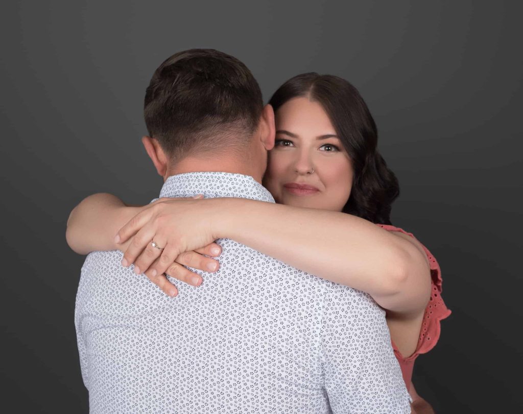 Engaged lady with her arms around her fiance's neck