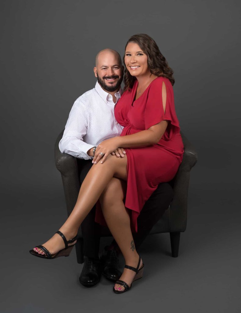 Lady in a red dress sitting on her husband's lap